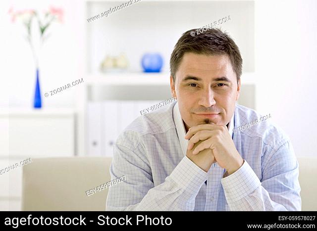Casual man sitting on sofa at home, thinking