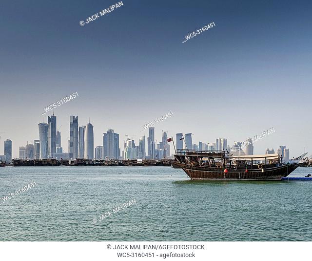 doha city skyscrapers urban skyline view and dhow boat in qatar