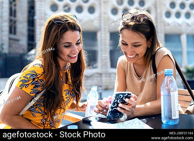 Women using mobile phone while sitting against Sagrada Familia at Barcelona, Catalonia, Spain