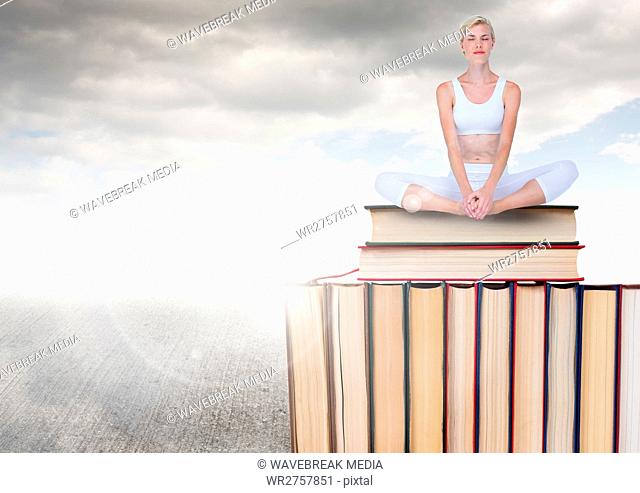 Woman meditating sitting on Books stacked by grey cloudy sky