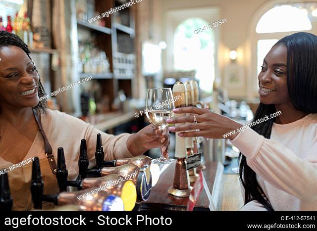 Friendly bartender serving white wine to woman in pub