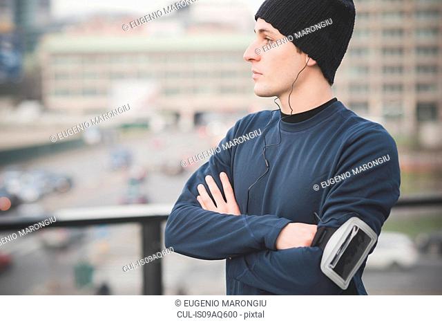 Portrait of young male runner looking out from footbridge