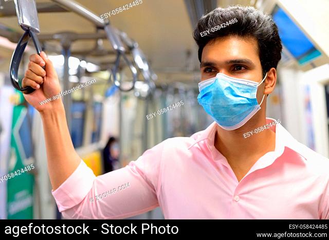 Portrait of young Indian businessman with mask for protection from corona virus outbreak social distancing at the skytrain station