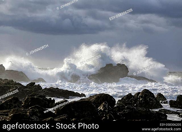 Sea wave splash. Rocky beach from the north of Portugal. Sky before rain