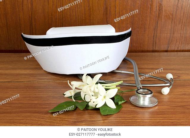Hat nurse white and Millingtonia hortensis flowers and stethoscope on wood table. symbol of nursing thailand and Thai traditional medicine