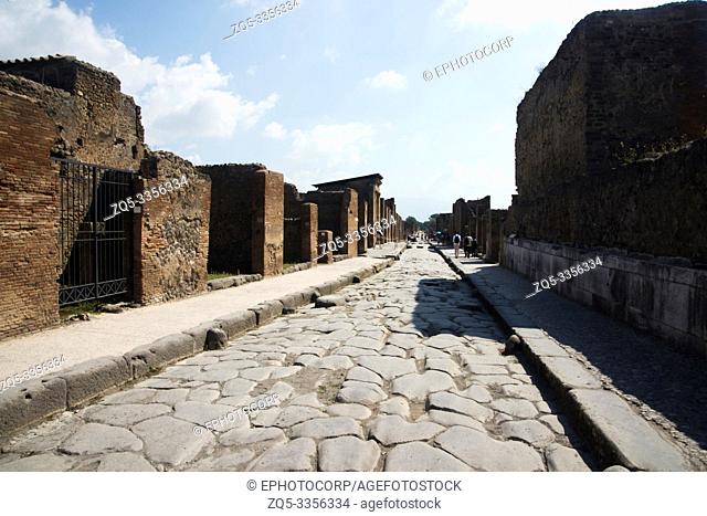 POMPEII, ITALY, July 2018, Tourist at street with pavements and big cobble stones, remains of the pillars and gateway