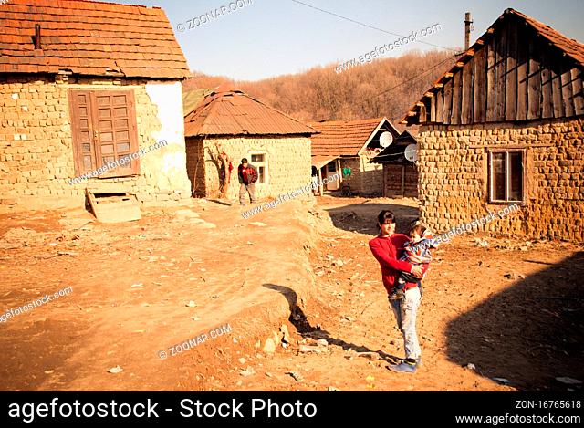 SEREDNIE, UKRAINE - MARCH 09, 2011: Teen mom holding son in her arms. Real life of peeople in poor remote settlements. Collapsing adobe houses built on soil on...