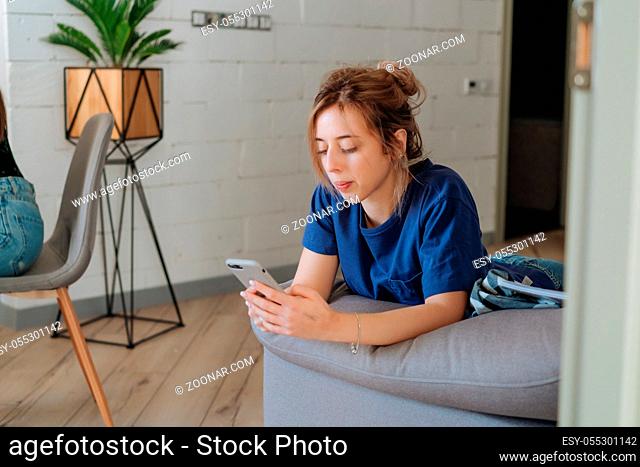 Pretty girl using her smartphone on couch at home in the living room