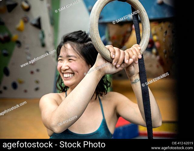 Smiling woman exercising at gymnastics rings