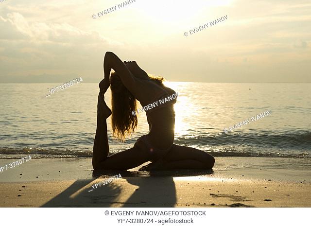 Silhouette of a pigeon pose yoga on the beach