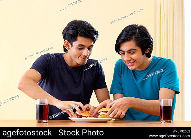 Portrait of teenage boys eating burgers together