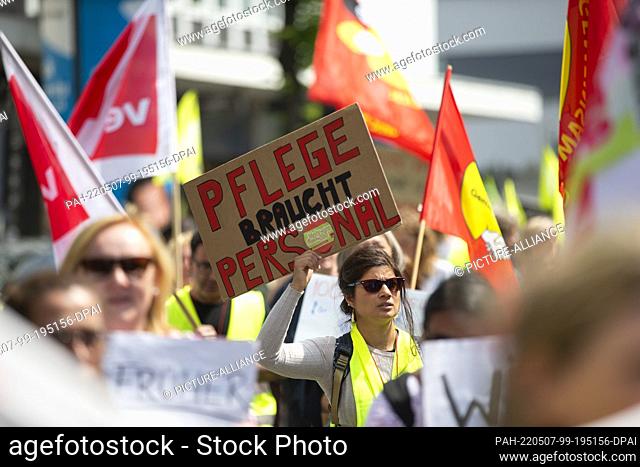 07 May 2022, North Rhine-Westphalia, Duesseldorf: A demonstrator carries a sign reading ""Pflege braucht Personal"" (""Nursing needs staff"")