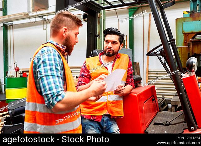 Staplerfahrer redet mit Kollegen an Gabelstapler in der Lagerhalle einer Metallfabrik