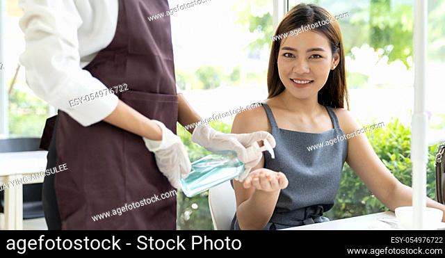 Panorama of waitress push alcohol gel hand sanitizer for customer at dining table for hygiene hand cleaning reduce infection of coronavirus covid-19 pandemic