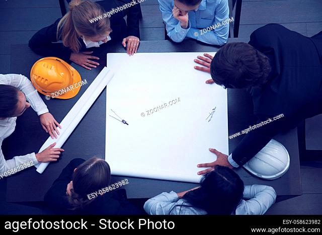 Top view of business people around the table in construction business meeting blank blueprint paper with copy space for text