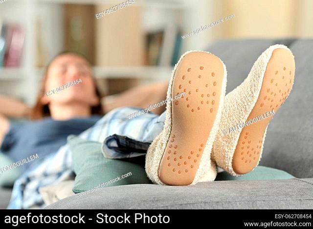 Happy woman wearing slippers resting lying on a couch at home