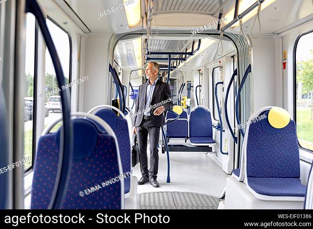 Businessman holding briefcase while standing in tram