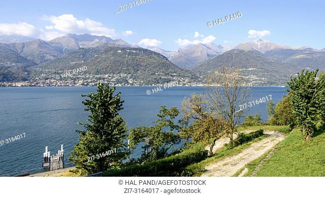 landscape of green Como lake with landing at historical abbey, shot in bright fall light at Piona, Como, Italy