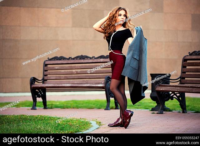 Young fashion woman with long curly hairs walking on city street
