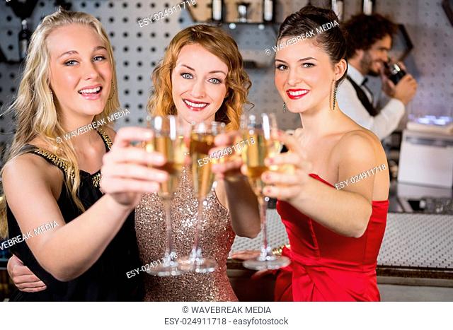 Three smiling friend showing glass of champagne