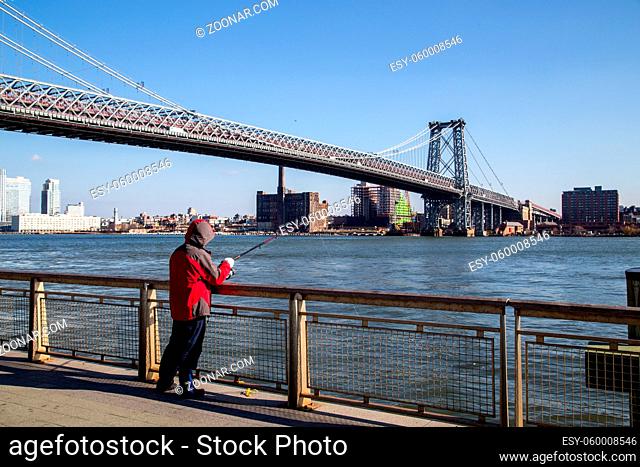 New York, United States of America - November 17, 2016: A man fishing at the Williamsburg Bridge in Manhattan in New York City