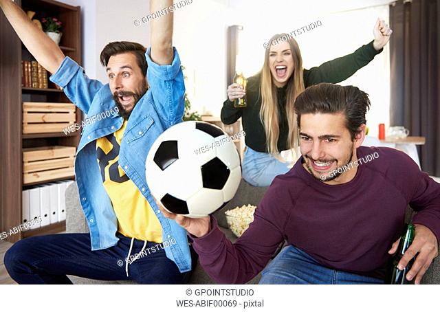Excited football fans watching Tv and cheering