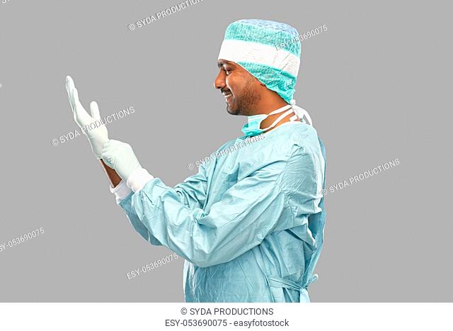 indian male doctor or surgeon putting glove on