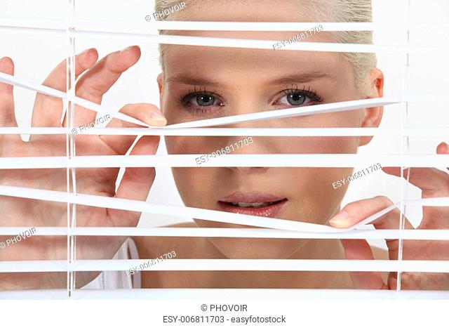 young woman looking through the blinds