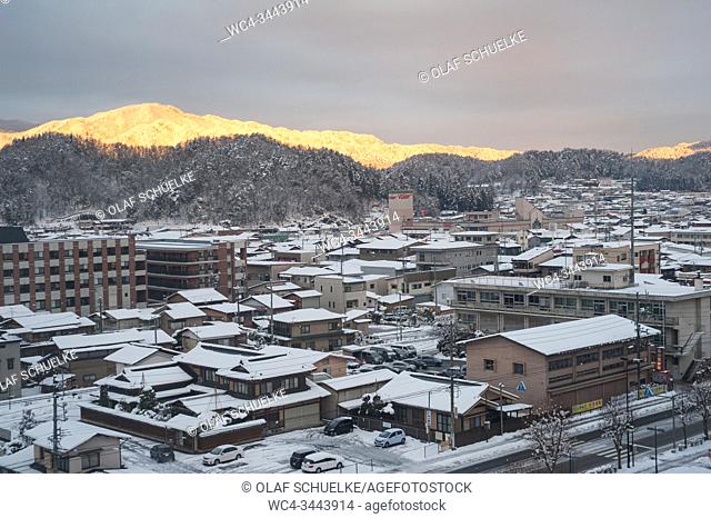 Takayama, Gifu, Japan, Asia - A view from above of the snow-covered roofs of the houses and the streets of the city with mountains in the backdrop