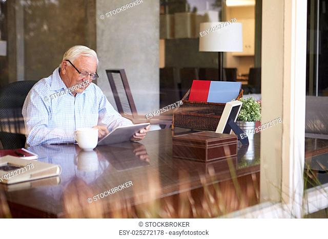 Senior Man Using Digital Tablet Through Window
