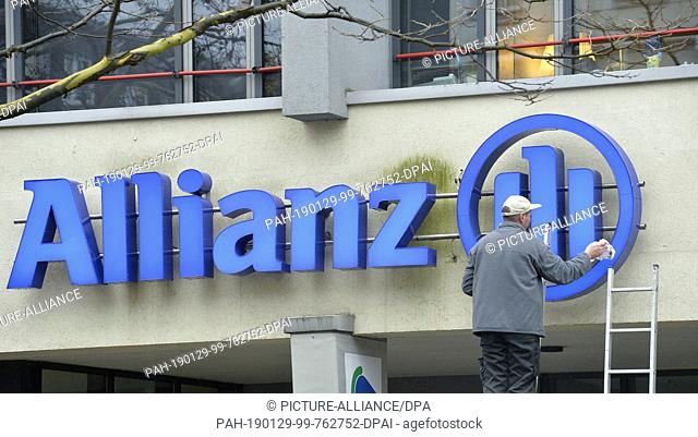 07 December 2018, Saxony, Leipzig: A man cleans a lettering of the insurance company ""Allianz"" on a building in Leipzig
