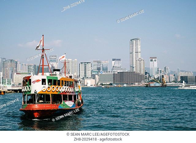 A ferry boat sails across Hong Kong bay against a bright blue sky