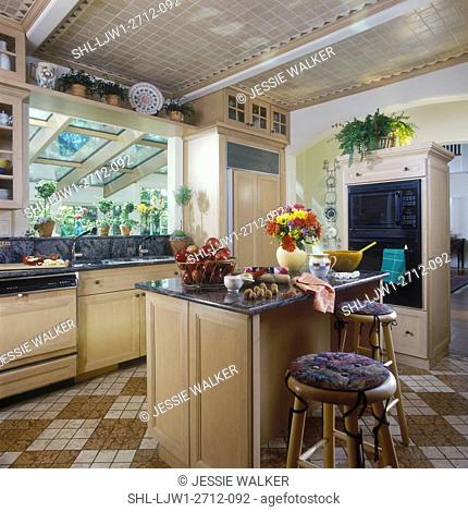 KITCHENS: Light color wood cabinets, light tan ceramic tile ceiling, granite countertops, view towards island and sink area, topiaries on ledge, tile ceiling