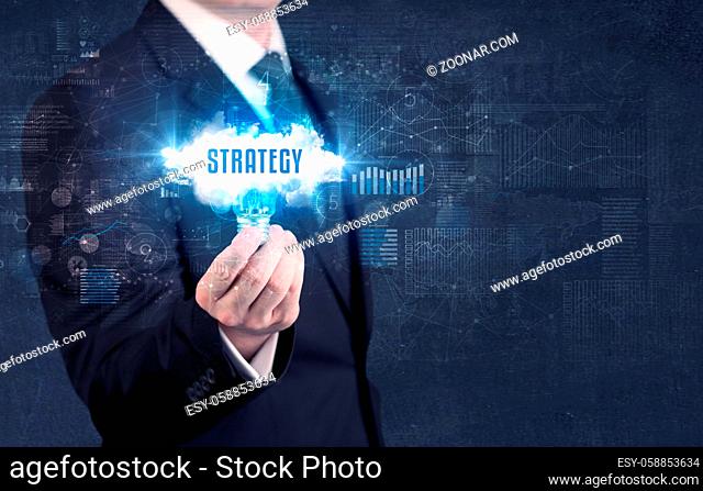 Businessman holding a light bulb with STRATEGY inscription, new business concept