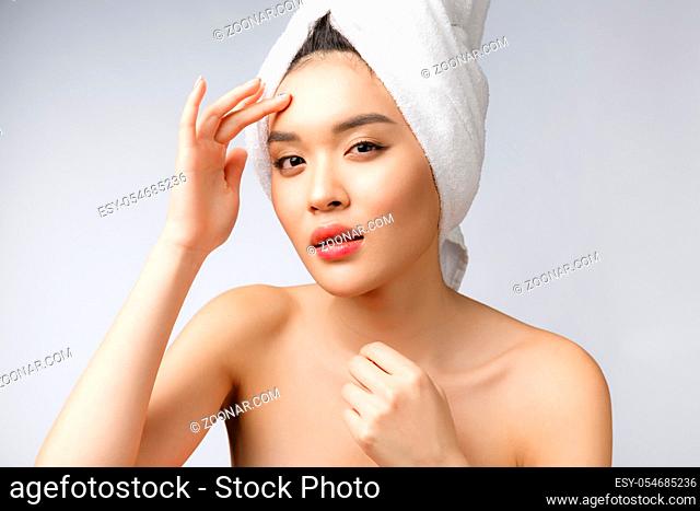 Asian woman looking at pimple on face. Young Woman try to remove her pimple. Woman skin care concept. Isolated on white background