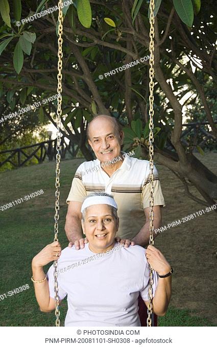 Man pushing woman on a swing and smiling, New Delhi, India