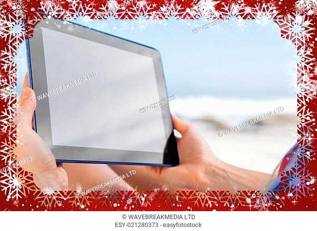 Woman sitting on beach in deck chair using tablet pc