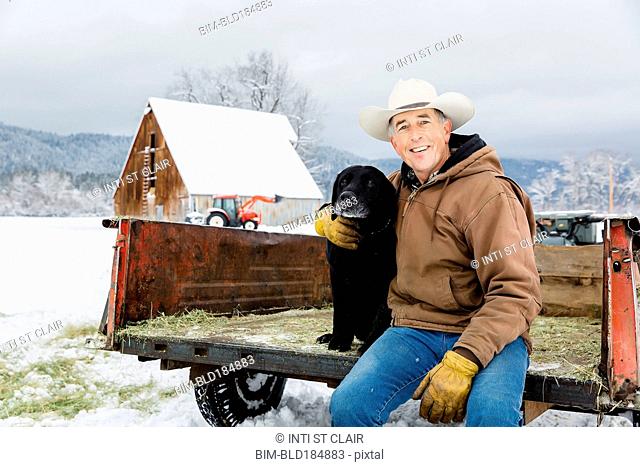 Caucasian farmer hugging dog in snowy truck