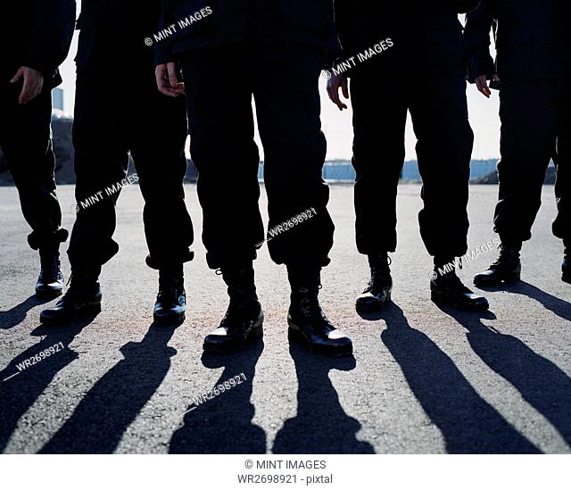 Low angle view of row of men wearing military uniforms, casting shadows