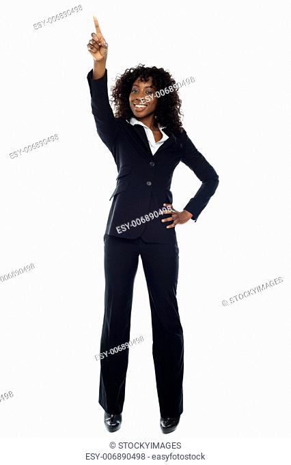 Smiling business executive pointing upwards with one hand on her waist