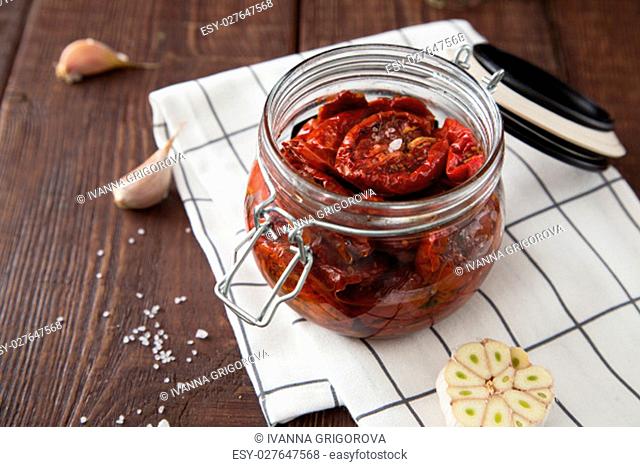 Sun dried tomatoes with herbs and sea salt in olive oil in a glass jar