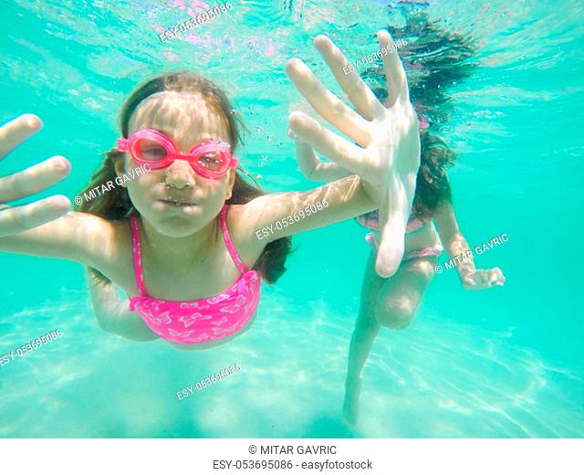 Happy child underwater portrait - Little girl wearing swimming goggles dive and swim in the seawater - Summer vacation fun