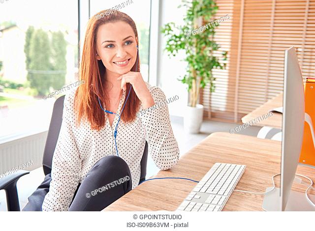Portrait of woman at desk looking away smiling