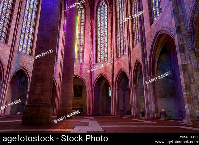 The nave of the church of the Jacobins, a 13th century church, lit up at night, with tall pillars with coloured lights
