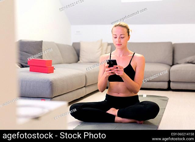 Beautiful blonde woman doing home workout indoors. Woman practice yoga at home. Fit girl using workout tutorials for healthy active lifestyle