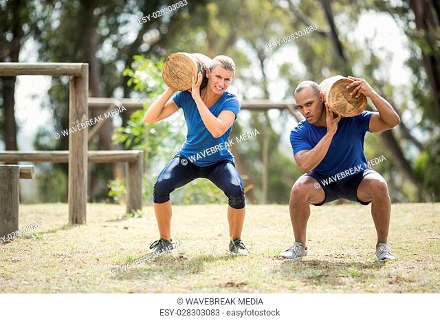 People carrying heavy wooden logs during obstacle course