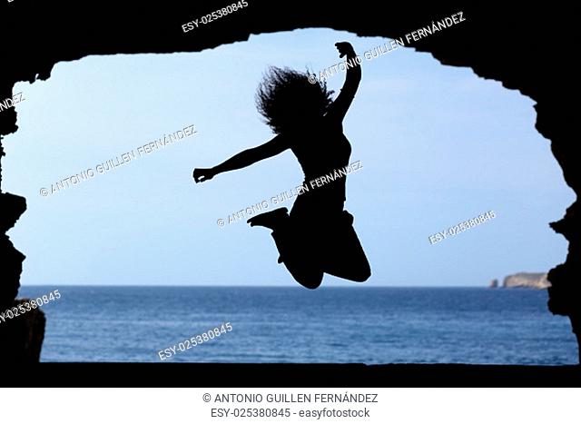 Silhouette of a woman jumping on the beach with the sea in the background isolated on black background