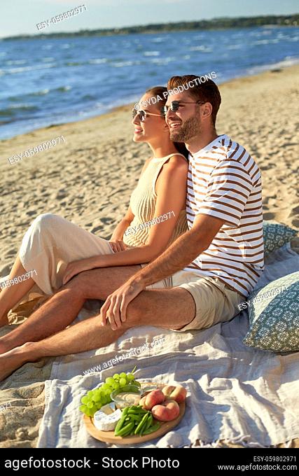 happy couple having picnic on summer beach