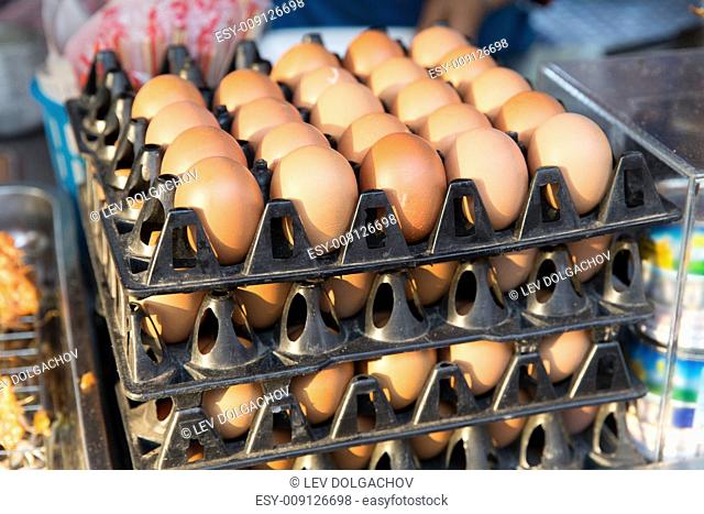 cooking, asian kitchen, sale and food concept - fresh eggs on tray at asian street market