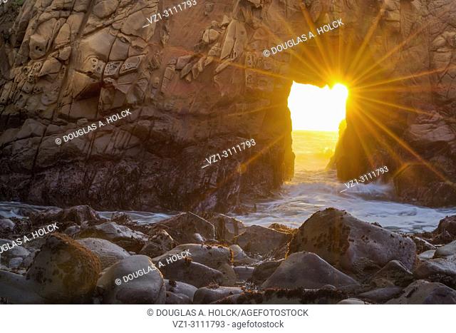Rays of sunlight shine through iconic Pfeiffer Beach Arch, Big Sur, California, USA